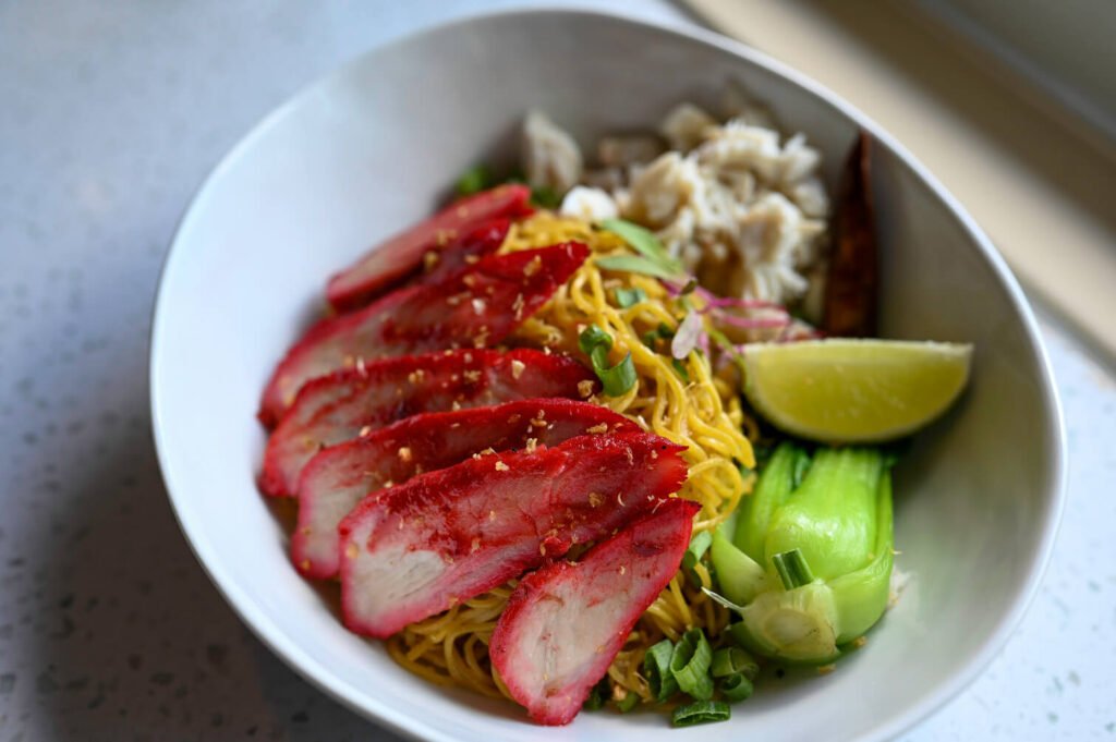 A flavorful bowl of noodles from Bakmi Lim Noodle Project, topped with fresh ingredients and savory sauce.